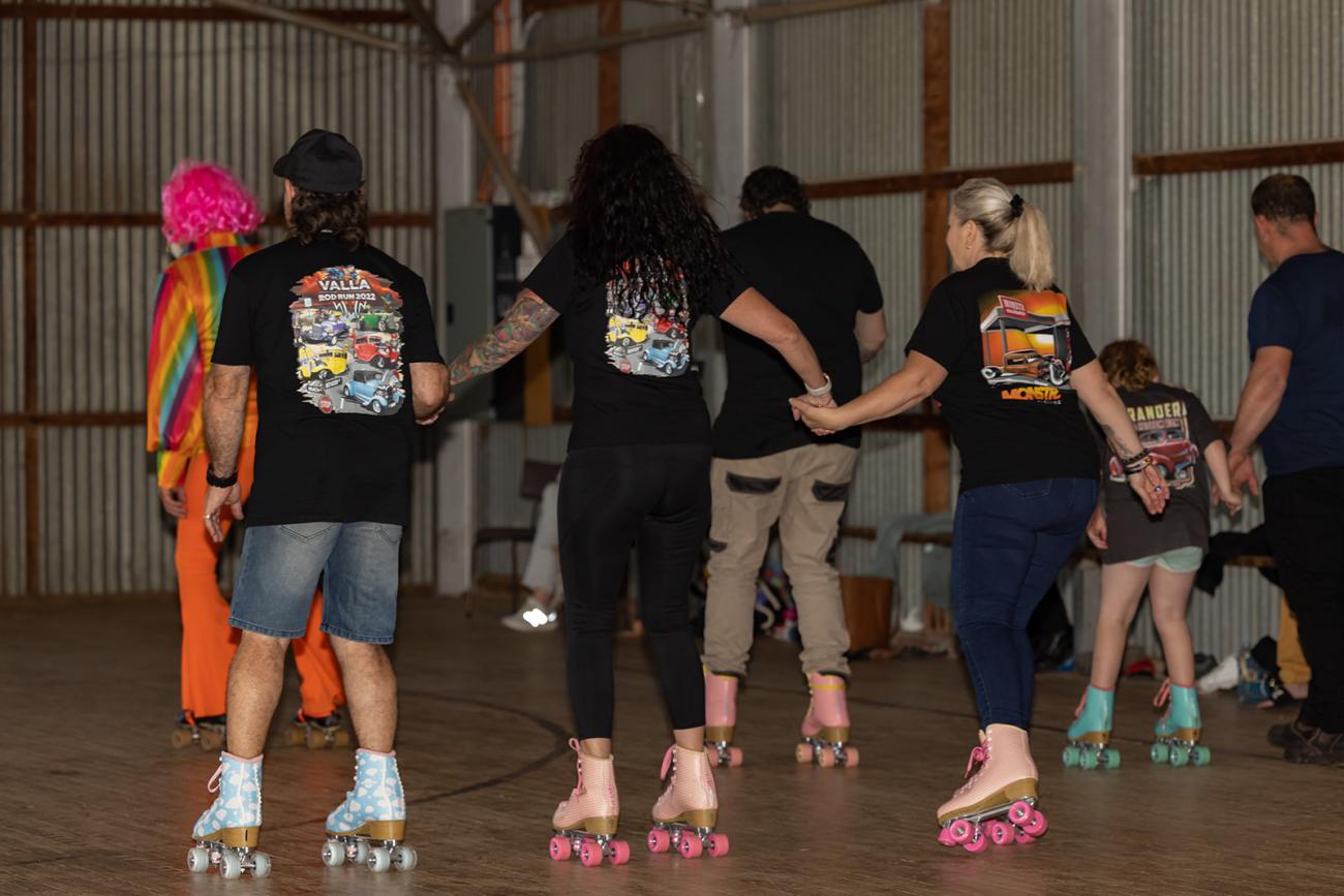 four people roller skating while holding hands